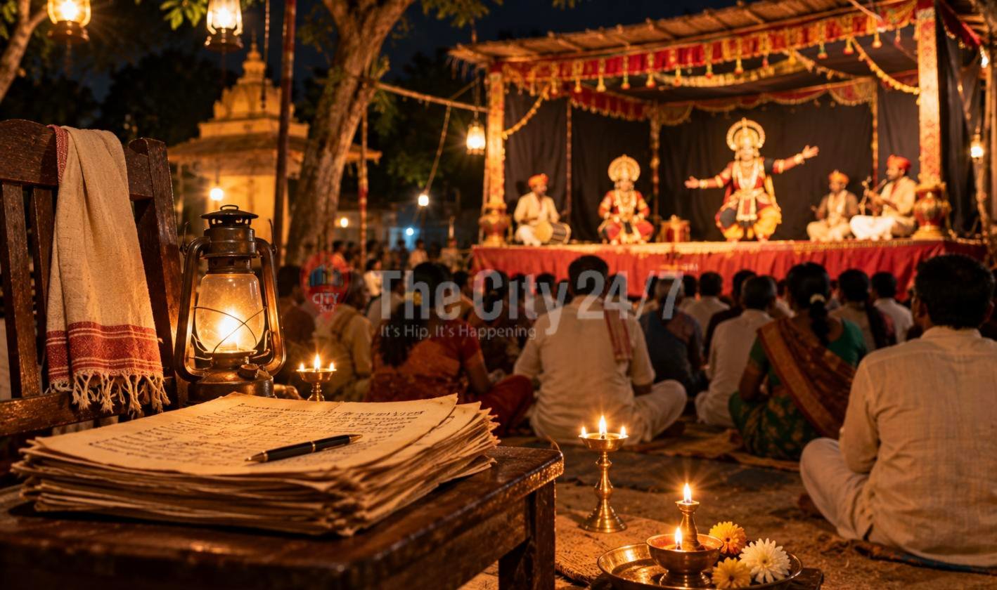 A lantern and a stack of handwritten manuscript pages on a wooden table as villagers watch costumed folk theatre performers on a lamplit stage at night